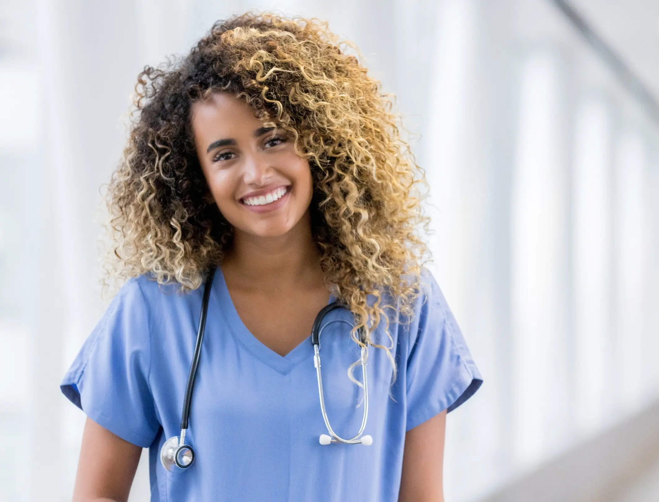 A friendly hospice nurse stands and smiles