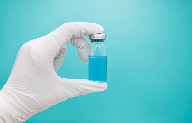 A lab working holding a bottle of medicine