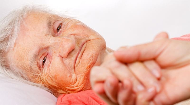 A senior patient holding hands with a caregiver