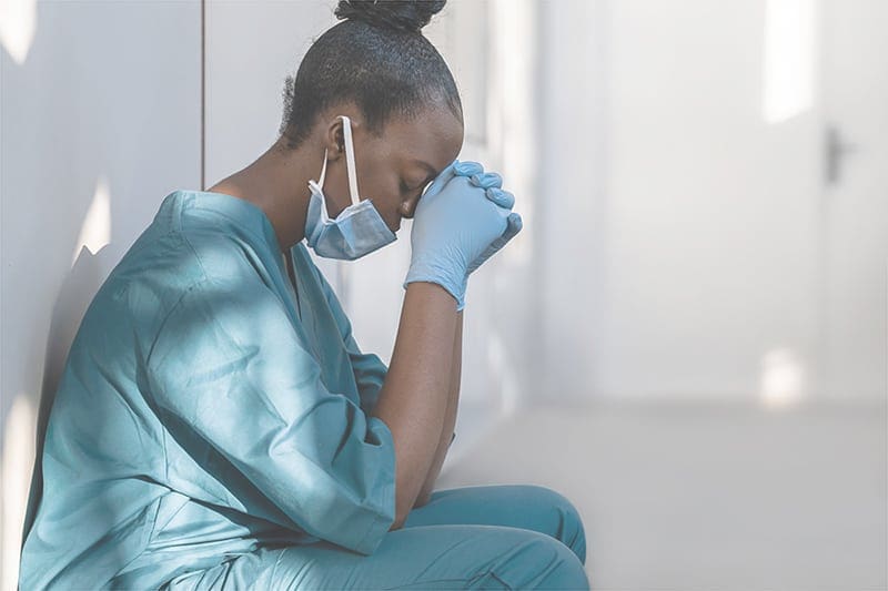 A nurse bending down and resting her head